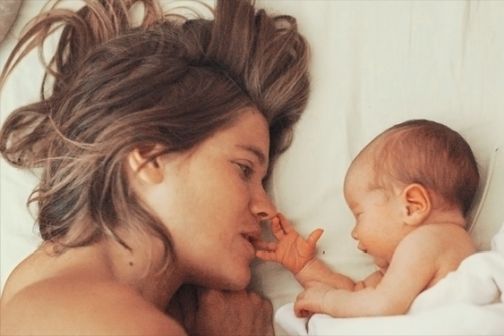 Bild von Frau mit ihrem Baby im Bett kuschelnd